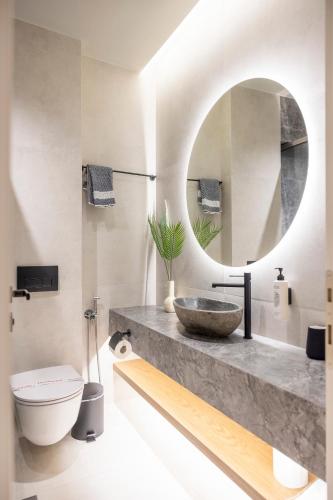 a bathroom with a sink and a toilet and a mirror at Polyzos Luxury Suites Meteora #1 - Adults Friendly in Kalabaka