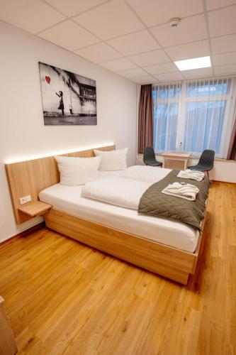 a large bed in a room with two chairs at Sonnenschein Hotel & Apartments in Heilbad Heiligenstadt