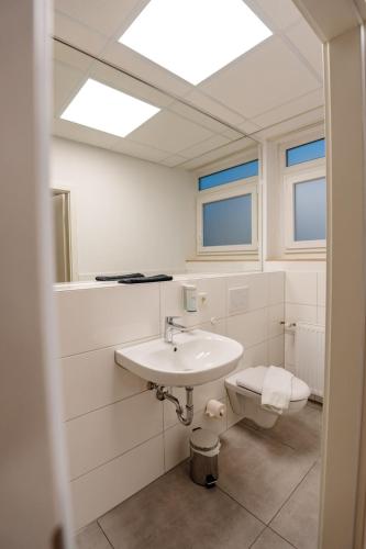 a bathroom with a sink and a toilet at Sonnenschein Hotel & Apartments in Heilbad Heiligenstadt