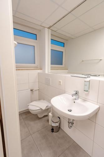 a white bathroom with a sink and a toilet at Sonnenschein Hotel & Apartments in Heilbad Heiligenstadt