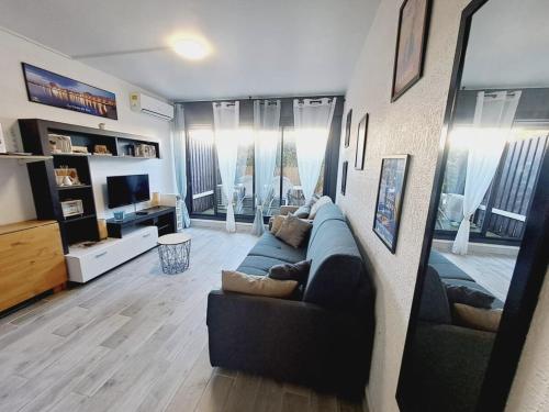 un salon avec un canapé bleu et une télévision dans l'établissement Joli studio à deux pas de la mer, au Grau-du-Roi