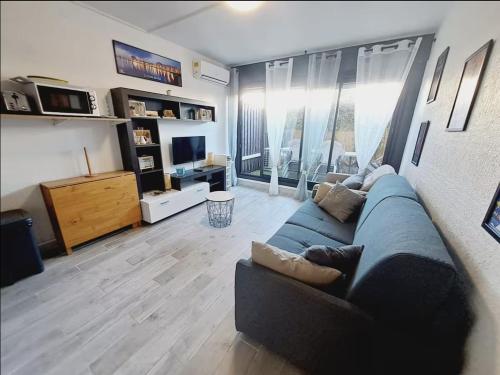 un salon avec un canapé bleu et une télévision dans l'établissement Joli studio à deux pas de la mer, au Grau-du-Roi