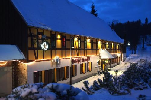 a building with a clock on it in the snow at Naturhotel Gasthof Bärenfels in Kurort Altenberg