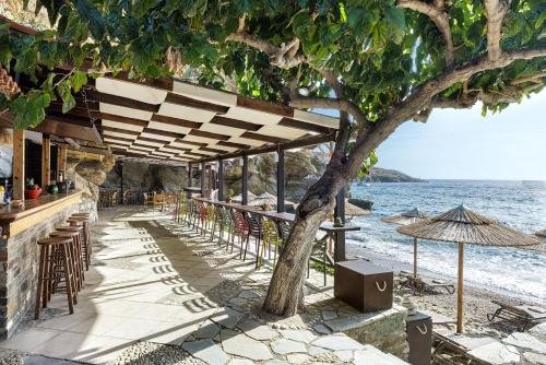 a bar on the beach with chairs and an umbrella at Aneroussa Beach Hotel in Batsi