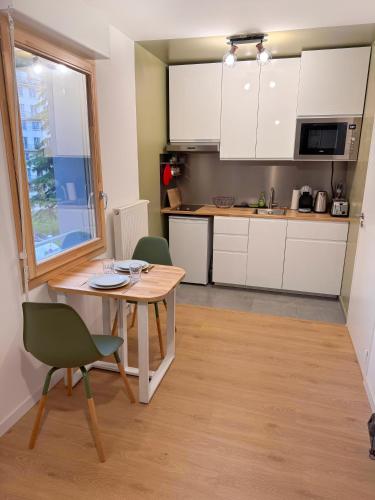 une cuisine avec des armoires blanches et une table et des chaises dans l'établissement Grand studio neuf Bagneux proche transport métro 4 Paris, à Bagneux