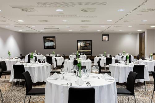 a banquet room with white tables and black chairs at AC Hotel by Marriott Bratislava Old Town in Bratislava