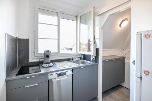 une petite cuisine avec un évier et une fenêtre dans l'établissement L'Évasion Normande - Appt à proximité de la plage, à Ouistreham