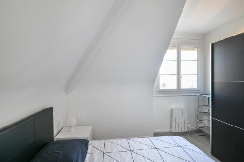 une chambre blanche avec un lit et une fenêtre dans l'établissement L'Évasion Normande - Appt à proximité de la plage, à Ouistreham