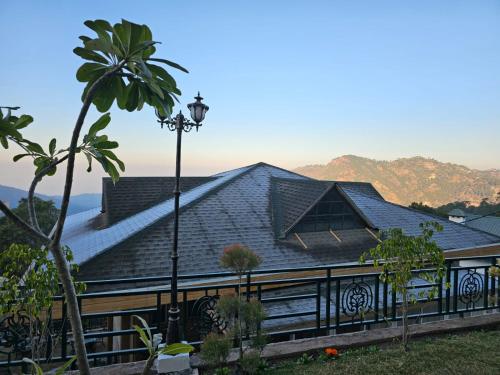a house with a black roof and a palm tree at Royalpine Rosastays Kasauli in Kasauli