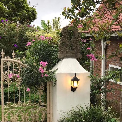 a garden gate with a light and a fence with flowers at green slope villa glamping in Gitgit