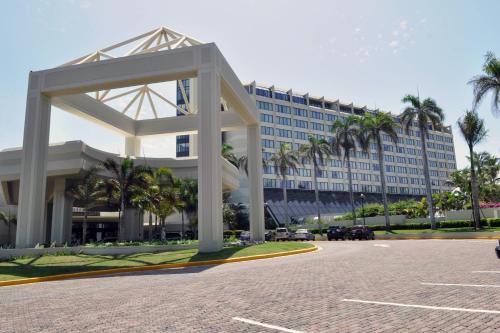 a large building with palm trees in front of it at Renaissance Santo Domingo Jaragua Hotel & Casino in Santo Domingo
