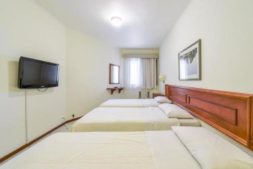 a room with four beds and a flat screen tv at Park Tower Campinas Residence by Nacional Inn in Campinas
