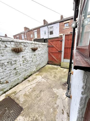 a brick retaining wall with a red gate and a fence at Modernised 3-bed home in Bamber Bridge, Preston in Bamber Bridge