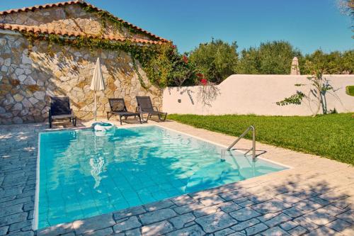 a swimming pool with two chairs and a house at Villa Hera Periyali in Vasilikos