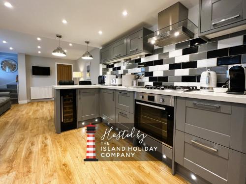a kitchen with grey cabinets and black and white tiles at Hope Cottage in Shanklin
