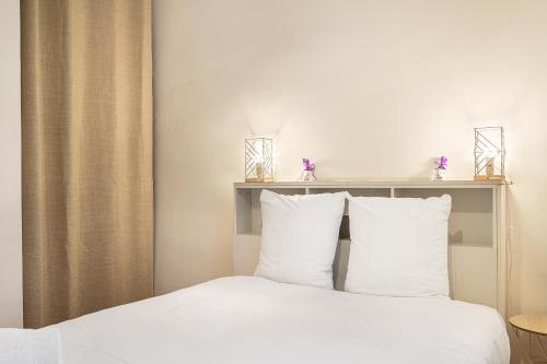 une chambre avec un lit avec des draps blancs et des oreillers dans l'établissement La Clé - Climatisation et WiFi au Centre de Toulon, à Toulon