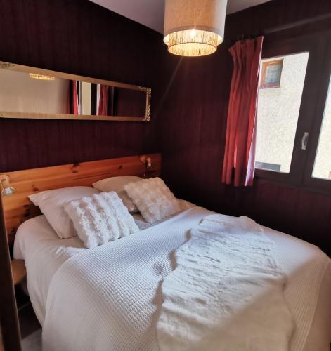 une chambre avec un lit avec des draps blancs et des oreillers dans l'établissement Les Campanules-Centre station, à Risoul