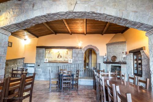 a dining room with tables and chairs and a stone wall at Agriturismo Le Querce in Bomarzo