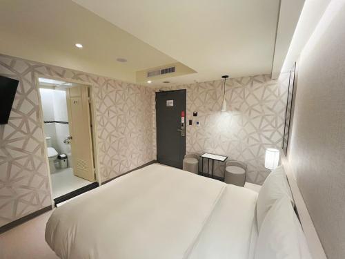 a bedroom with a large white bed and a bathroom at 新仕飯店-New City Hotel in Taipei