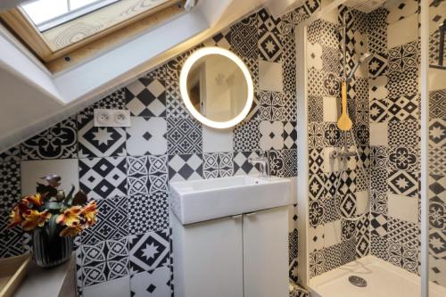 La salle de bains est pourvue de murs en carrelage noir et blanc et d'un lavabo. dans l'établissement Le Refuge Urbain - A 5 min à pied de la plage, à Trouville-sur-Mer