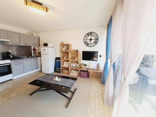 une cuisine avec une table et une horloge au mur dans l'établissement Le confort près de la plage, au Grau-du-Roi