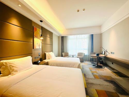 a hotel room with two beds and a desk at Holiday Inn Nantong Oasis International by IHG in Nantong