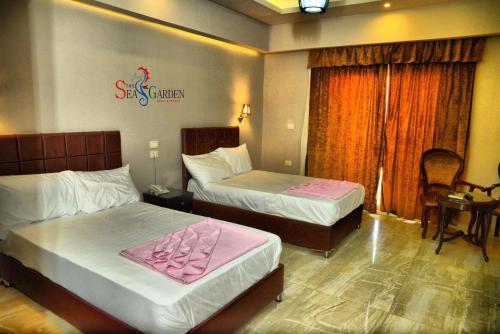 a hotel room with two beds with pink sheets at La mer Hotel in Alexandria