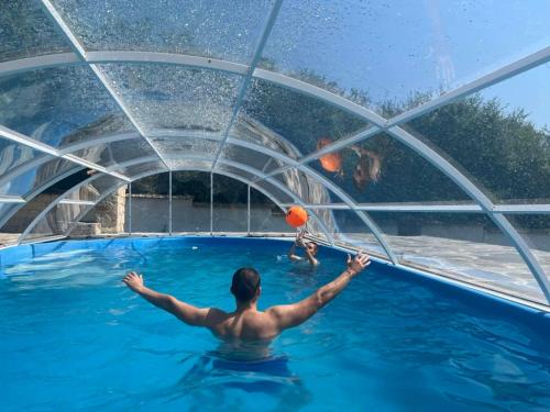 a man in the water playing with a ball in a swimming pool at Къща за гости Становец in Stanovets