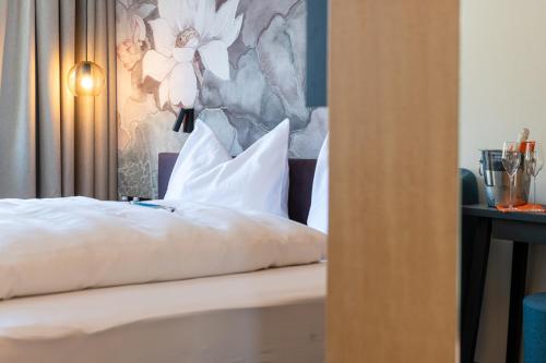 a bed with white pillows and a floral wall at Haus der Begegnung in Innsbruck