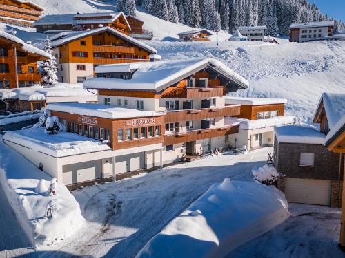 a resort in the snow with snow covered buildings at Hotel Garni Krumbach in Damuls