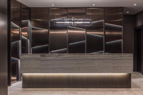 a bar in a hotel with a wall of metal at AC Hotel by Marriott Boston Cleveland Circle in Boston
