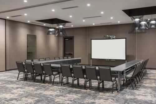 a conference room with a table and chairs and a white screen at AC Hotel by Marriott Boston Cleveland Circle in Boston