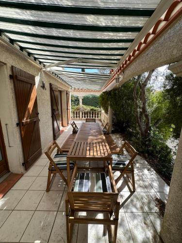 une rangée de tables en bois sur une terrasse dans l'établissement Maison roquefort-des-corbières, à Roquefort-des-Corbières