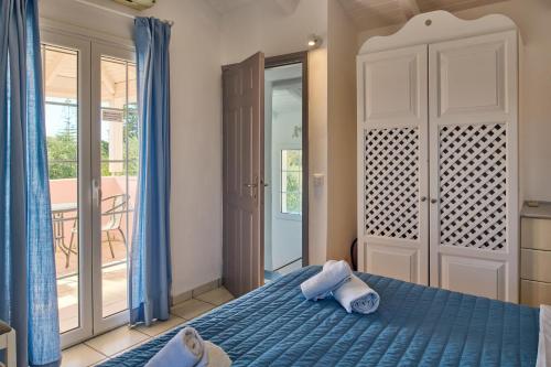 une chambre avec un lit bleu et un balcon dans l'établissement Villa Penelope Periyali, à Vasilikos