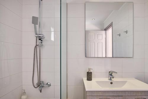 une salle de bain avec une douche avec un lavabo et un miroir dans l'établissement Villa Penelope Periyali, à Vasilikos