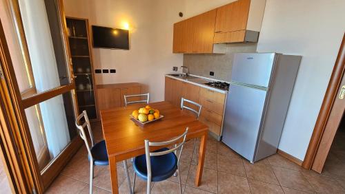a kitchen with a wooden table and a refrigerator at Residence Borgo Dei Limoni - Appartamenti con Garage in Gargnano