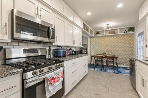 a kitchen with white cabinets and a stove top oven at Tulsa Expo Firepit Midtown House in Tulsa