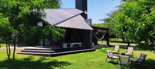 a house with chairs and a table in the grass at LunaNegra Casas de descanso in Villa General Belgrano