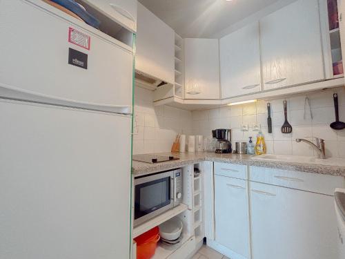 Elle comprend une petite cuisine avec des placards blancs et un réfrigérateur. dans l'établissement Central avec jardin, piscine parking 150 m plage, Fréjus, à Fréjus