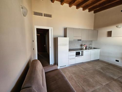 a kitchen with white cabinets and a couch in a room at Residence Borgo Dei Limoni - Appartamenti con Garage in Gargnano