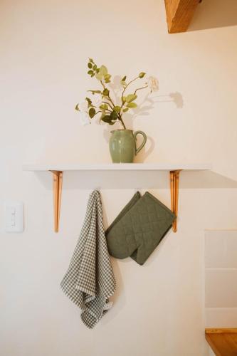 a white shelf with a plant on a wall at The Loft House in Graaff-Reinet