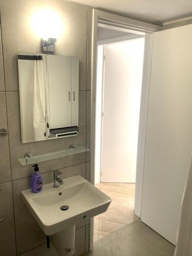 a bathroom with a sink and a mirror and a door at Mediterranean Apartments 2 in Paphos
