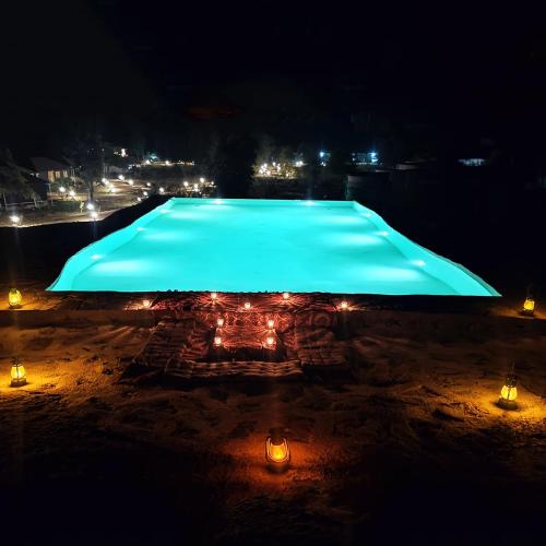 a large swimming pool at night with lights at Thour Nature Resort - Jawai Leopard Safari Camp in Bera