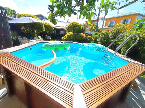 a swimming pool with a wooden bench in a backyard at Chambre privée 2 - Case créole Le Mistral,chez Kévin in Saint-André