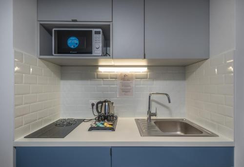 a kitchen counter with a sink and a microwave at The Originals Résidence Paris Sud Villejuif in Villejuif