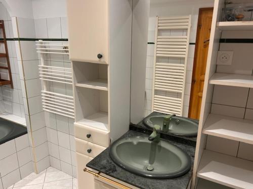 a small bathroom with a green sink and shelves at Maison de ville arborée avec cachet in Nanterre