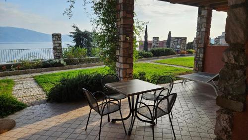 a table and chairs on a patio with a view of the water at Residence Borgo Dei Limoni - Appartamenti con Garage in Gargnano