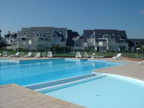 une grande piscine avec des chaises et une maison en arrière-plan dans l'établissement TADORNES 2 - Appartement duplex Carnac, Piscine - T130, à Carnac