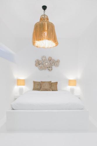 a bedroom with a white bed with a chandelier at Island Riviera Mykonos Villa in Agios Sostis Mykonos