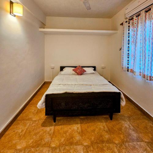 a bedroom with a bed with a red pillow on it at 2BHK Modern Apartment in Colva